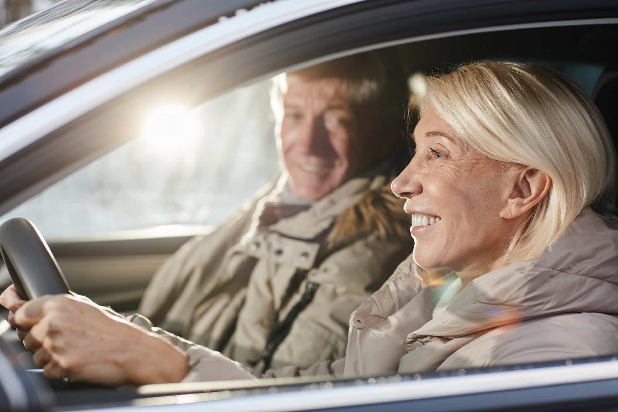 Senior koppel die in auto rijden met zon door het zijraam | rijbewijs keuren | Rijbewijsdokter