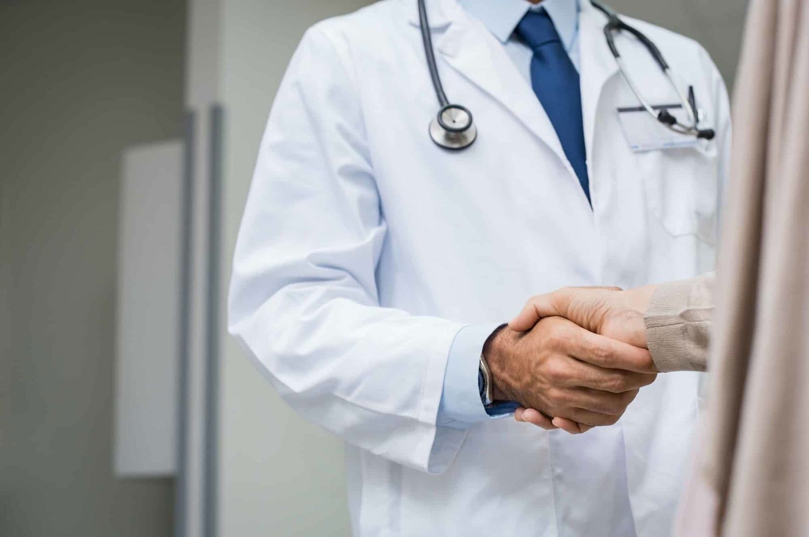 Dokter die een patiënt zijn hand schudt - Wat doet een keurdokter? - Rijbewijsdokter